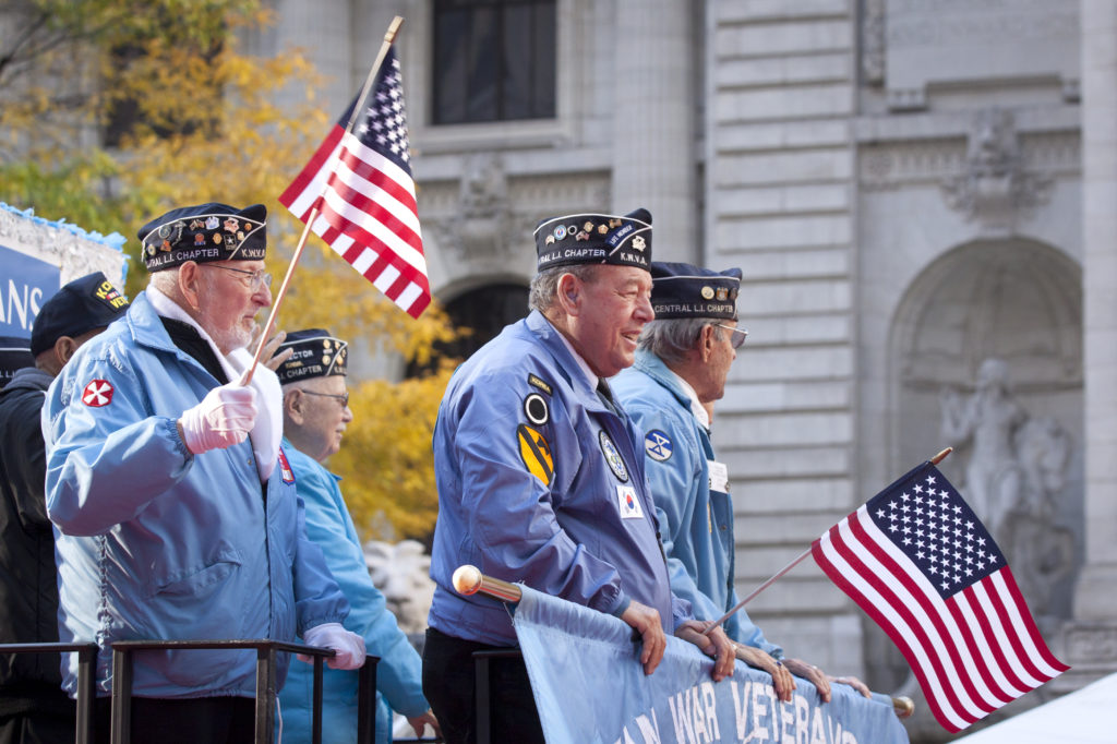 NEW YORK - NOV 11, 2014: US vets wave American Flags as they stand on a parade float in the 2014 America's Parade held on Veterans Day in New York City on November 11, 2014.