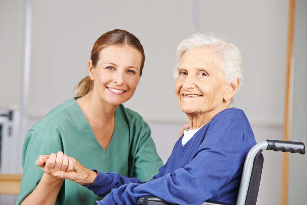 Geriatric care with nurse and happy senior woman in a wheelchair